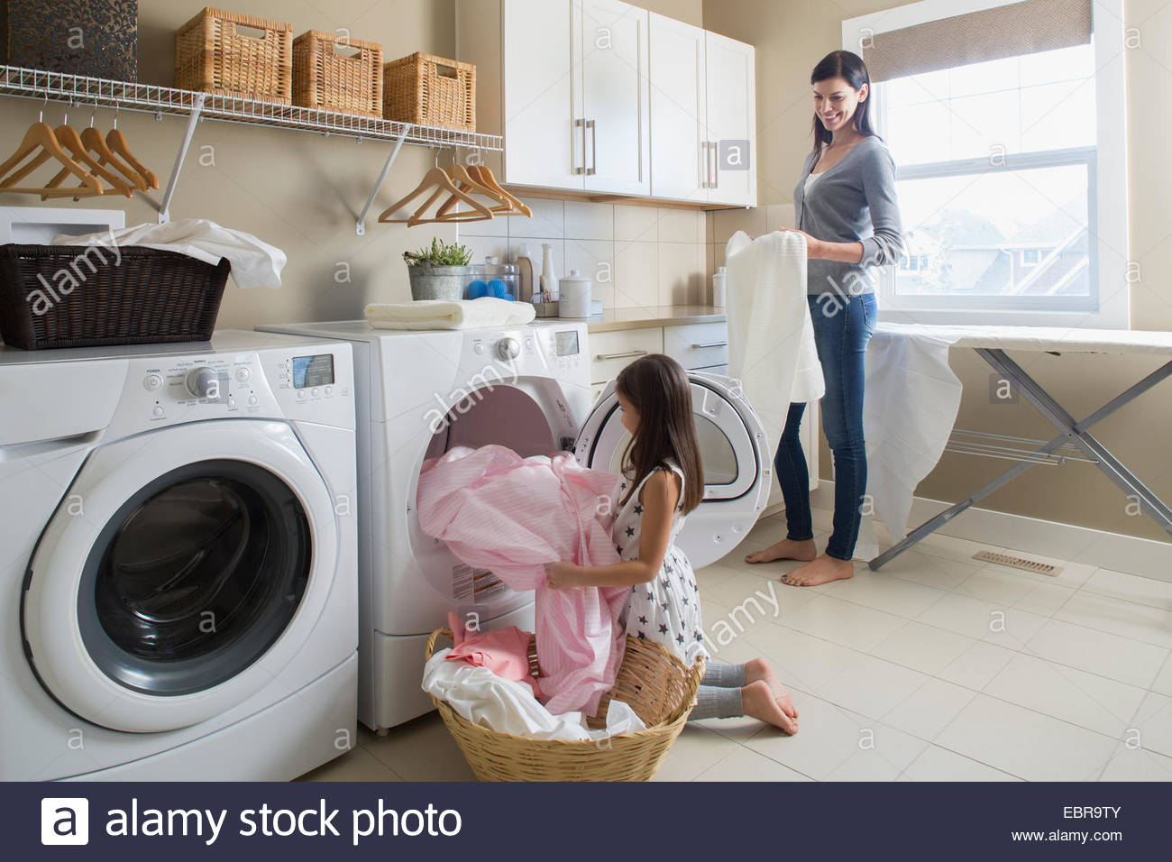 Mother and daughter in laundry room Stock Photo