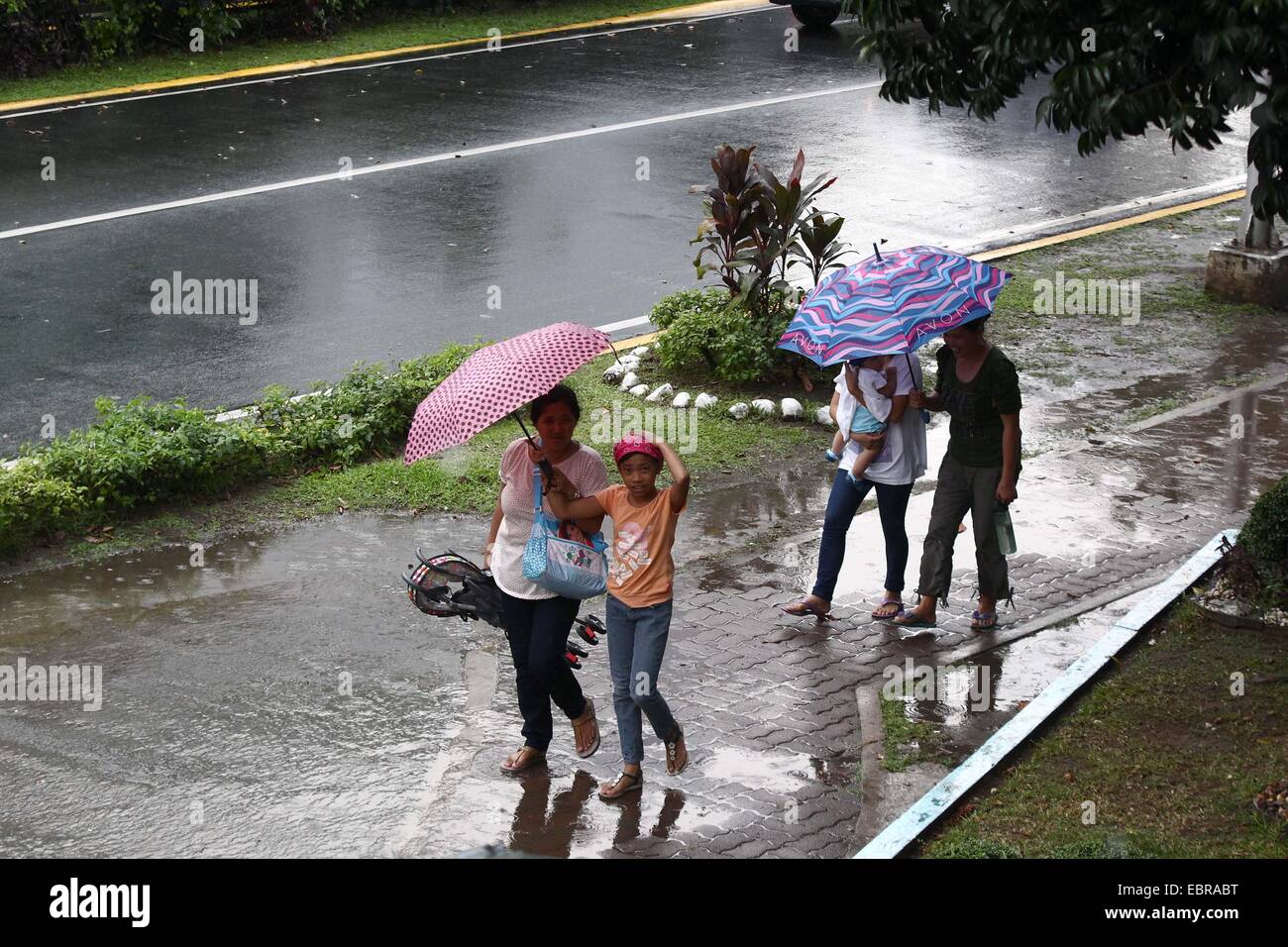 Quezon City, Philippines. 4th Dec, 2014. People walk with umbrellas in the rain in Quezon City, the Philippines, on Dec. 4, 2014. Typhoon Hagupit is packing maximum winds of 205 kph near the center and gustiness of up to 240 kph. The Philippine government will implement forced evacuation in areas that are expected to be hit by typhoon Hagupit (local name 'Ruby'), a senior government official said Thursday. Credit:  Rouelle Umali/Xinhua/Alamy Live News Stock Photo