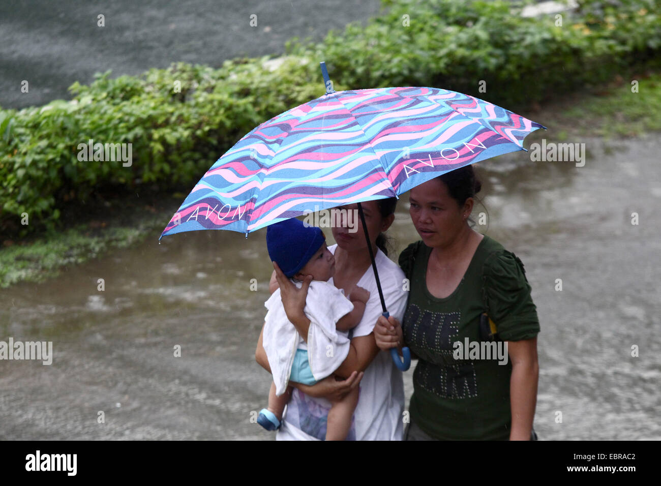 Quezon City, Philippines. 4th Dec, 2014. People walk with an umbrella in the rain in Quezon City, the Philippines, on Dec. 4, 2014. Typhoon Hagupit is packing maximum winds of 205 kph near the center and gustiness of up to 240 kph. The Philippine government will implement forced evacuation in areas that are expected to be hit by typhoon Hagupit (local name 'Ruby'), a senior government official said Thursday. Credit:  Rouelle Umali/Xinhua/Alamy Live News Stock Photo