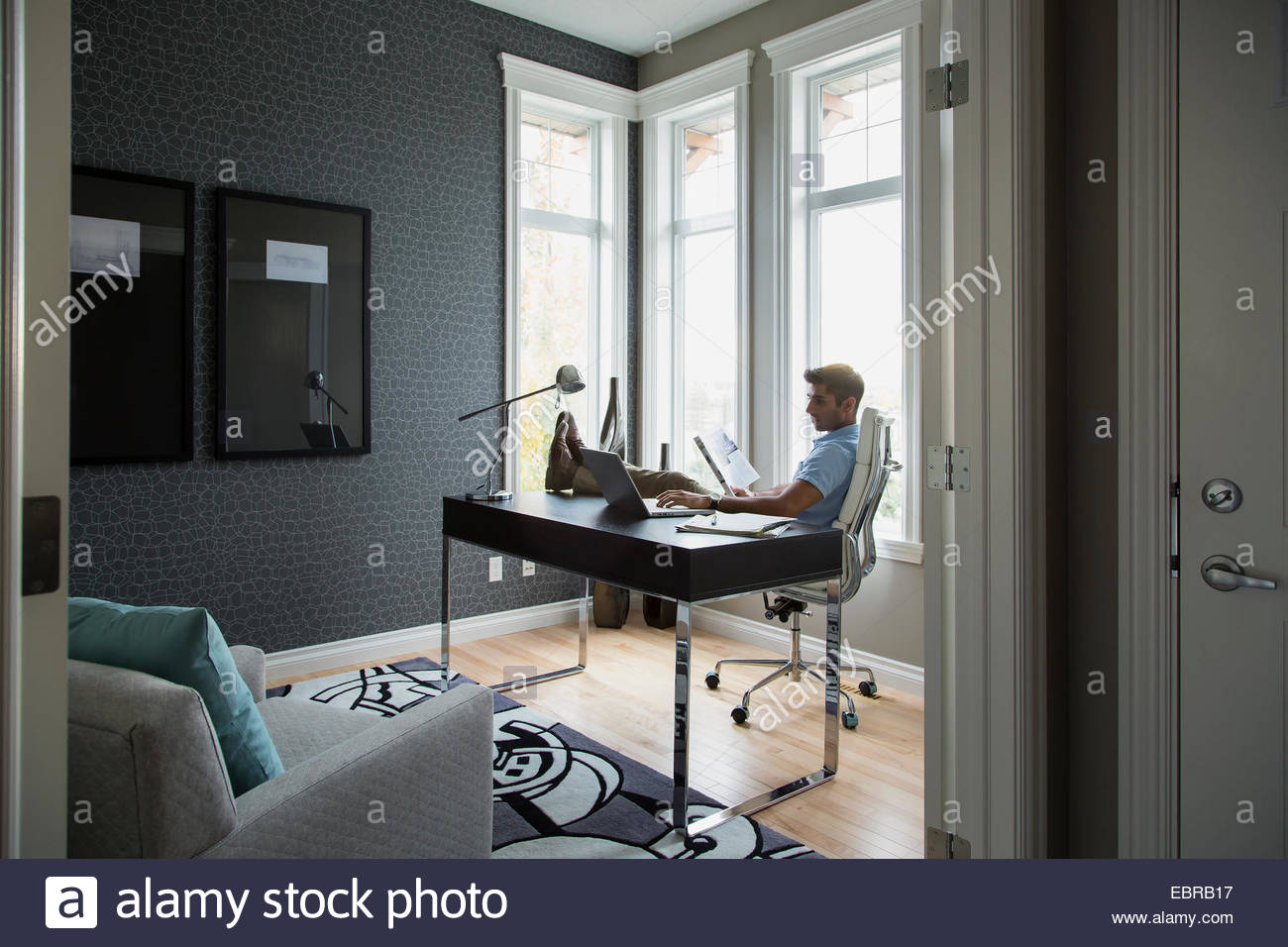 Man reading with feet up in home office Stock Photo