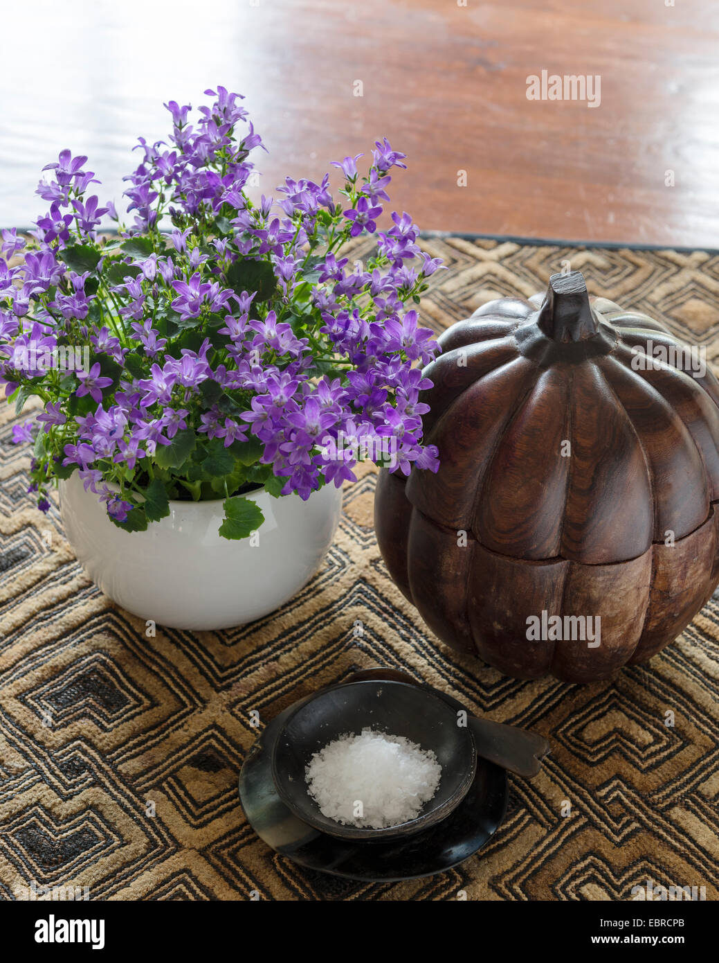 Purple flowering plant and salt dish with wooden carved pumpkin Stock Photo