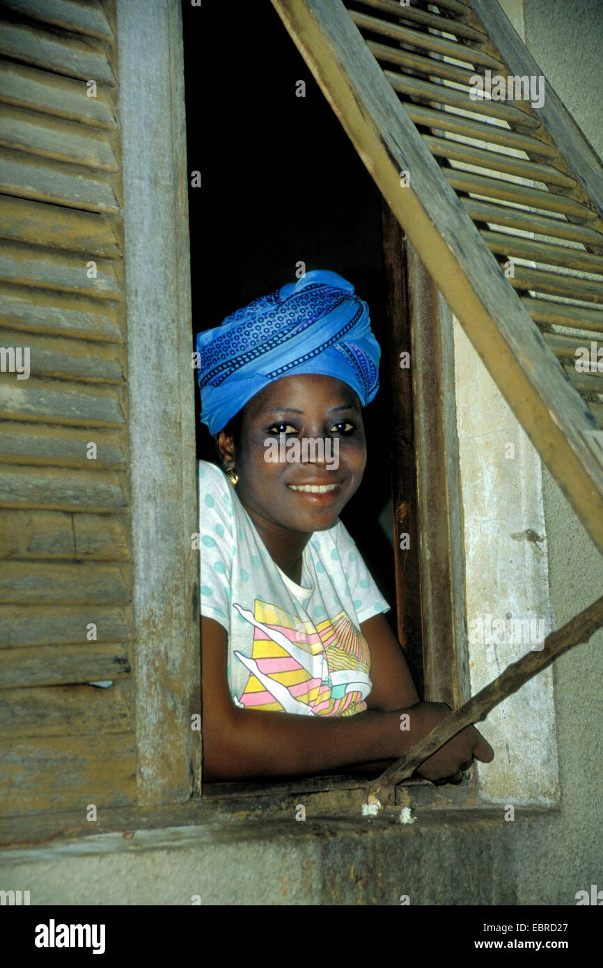 African woman looking out of an open window, Cote d'Ivoire Stock Photo