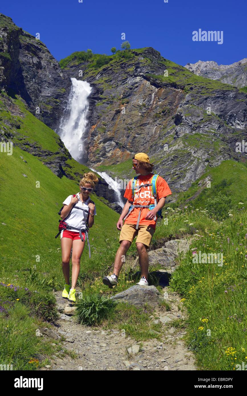 two wanderer on trekking path in front of waterfall of Laisonnay, France, Savoie, Vanoise National Park, Valley of Champagny Stock Photo