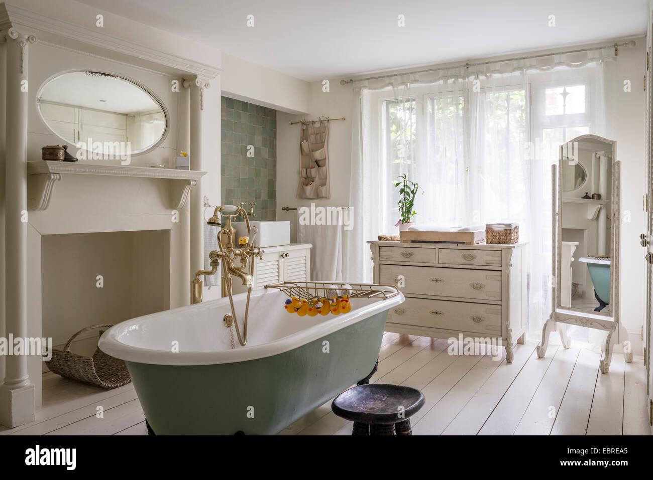 Freestanding roll-top bath with brass fittings in North London home Stock Photo