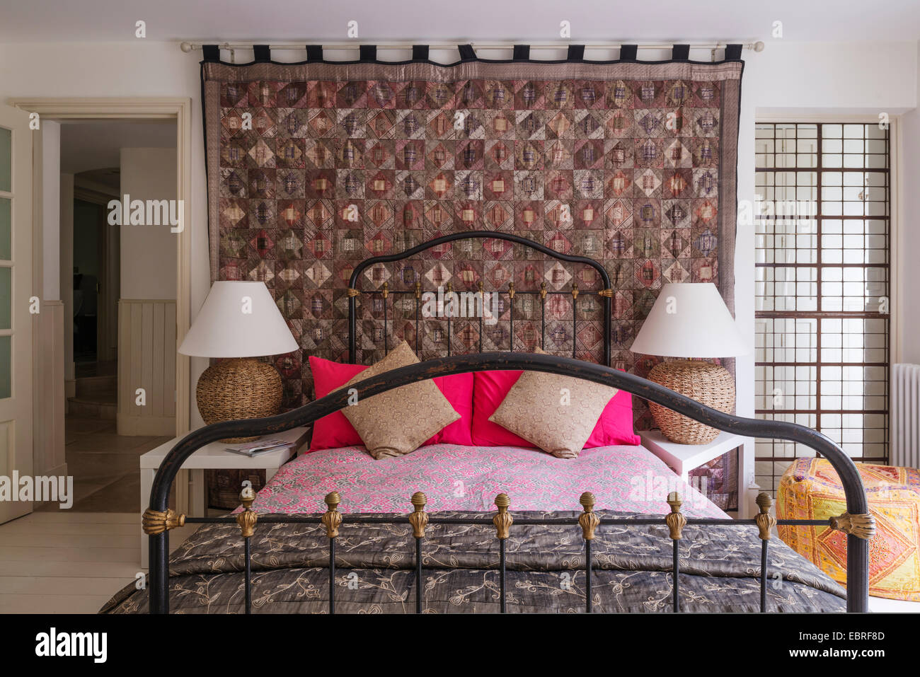 Patchwork wall hanging with metal framed bed in North London home Stock Photo