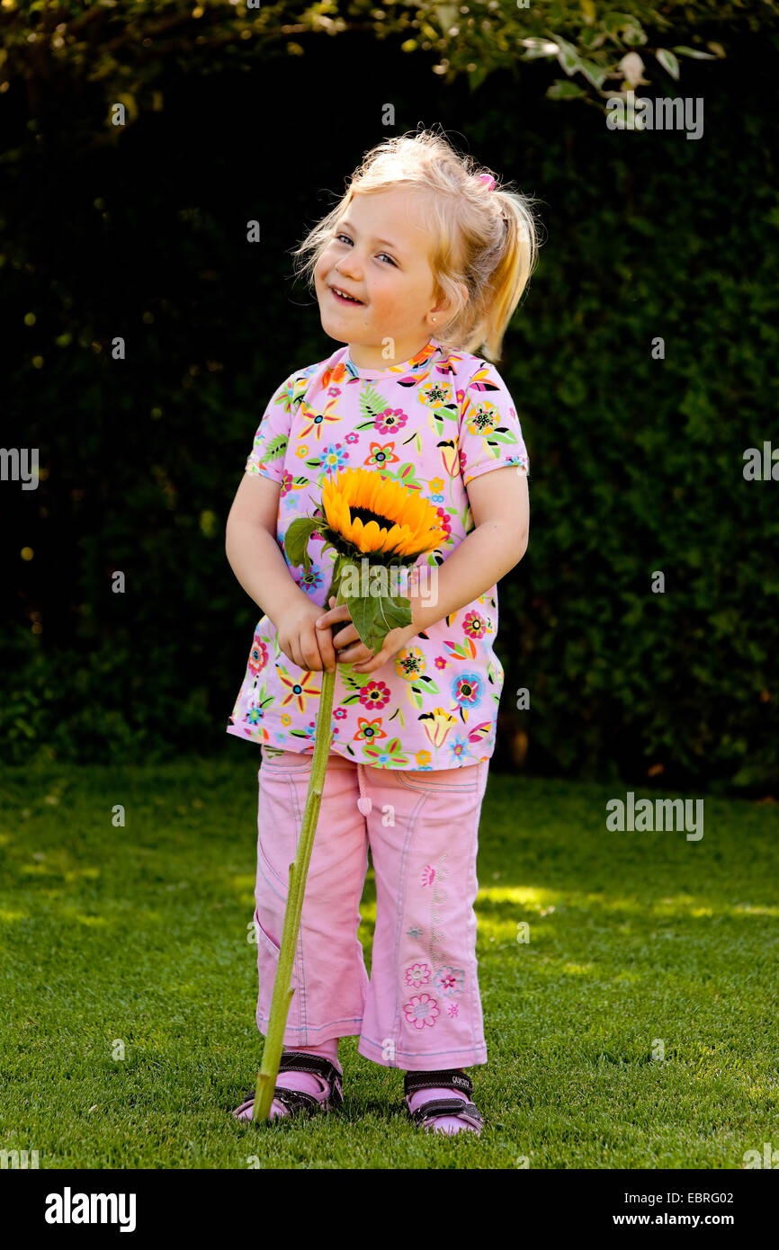 small child with a sun flower in the garden in summer Stock Photo