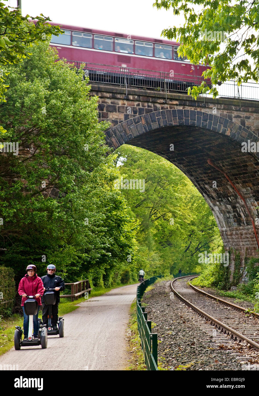 two tourists on Segways at Ruhr Valley Cycleway, historical railbus on viaduct, Germany, North Rhine-Westphalia, Ruhr Area, Witten Stock Photo