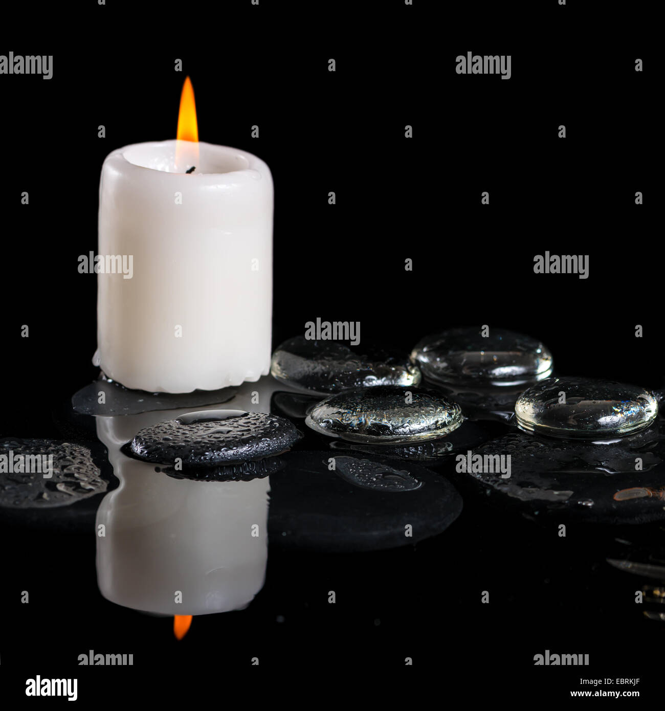 beautiful cryogenic spa concept of zen stones with drops, ice and candle on reflection water, closeup Stock Photo