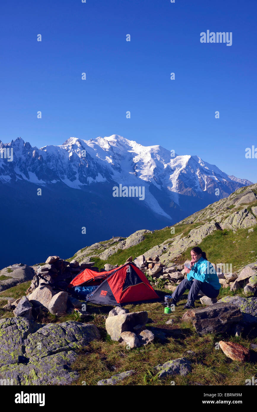 female mountain hiker pitched up a tent in the Alps, Mont Blanc  in background, France, Haute-Savoie, Chamonix Stock Photo