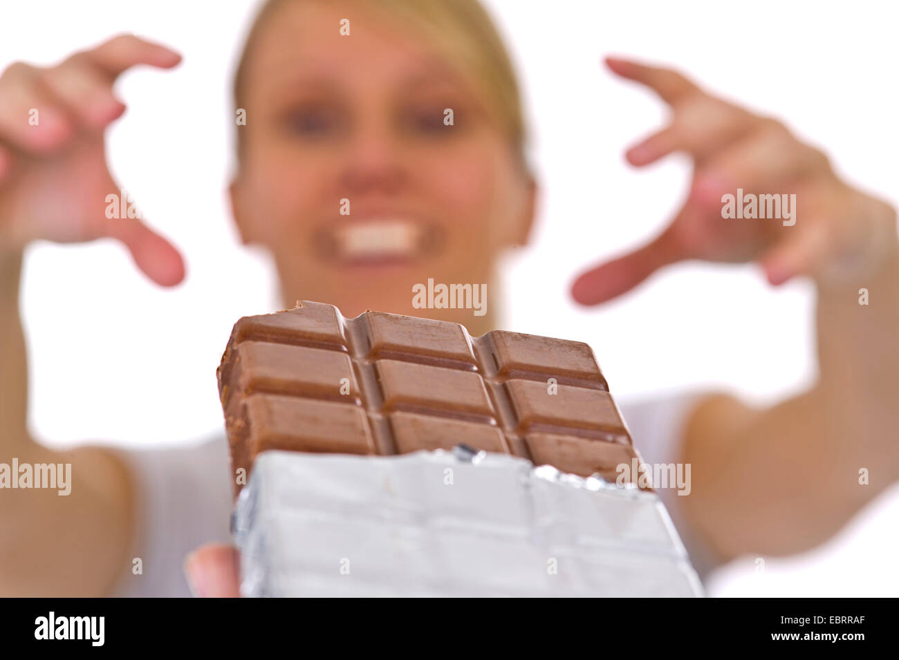 young woman greedily reaching out for a chocolate bar Stock Photo