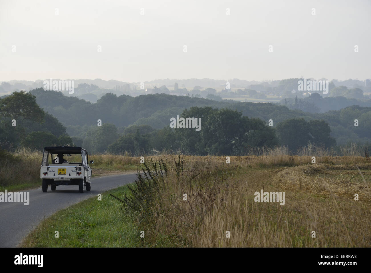 car driving through hilly field landscape in the morning, France, Brittany, Erquy Stock Photo