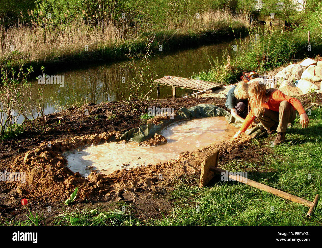 pond construction with loam and plastic film, children building a small pond, nesting aid for swallows, Germany Stock Photo