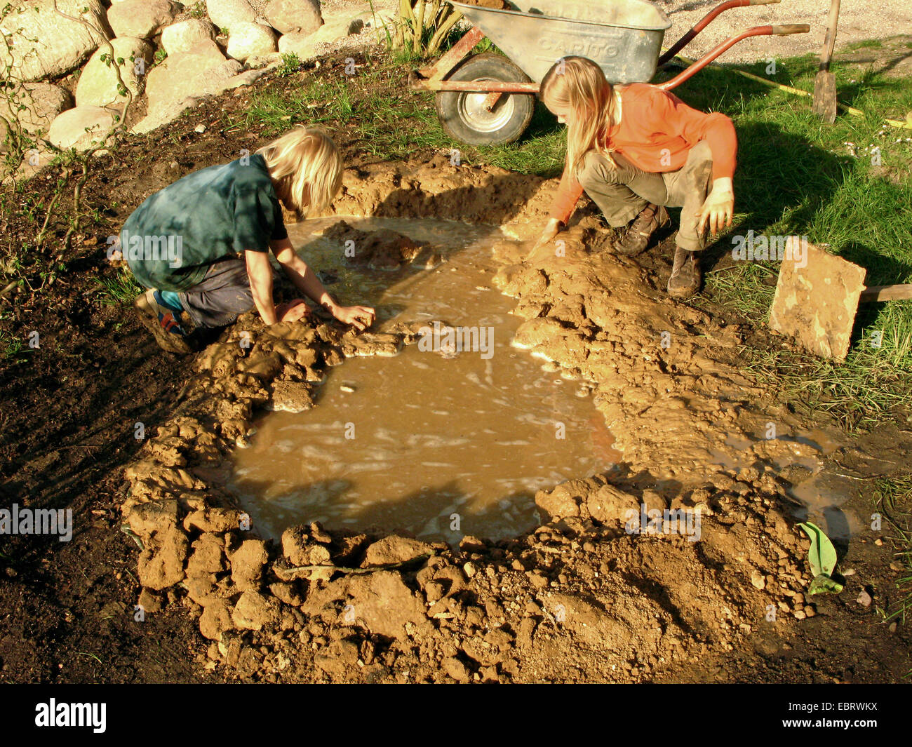 pond construction with loam and plastic film, children building a small pond, nesting aid for swallows, Germany Stock Photo