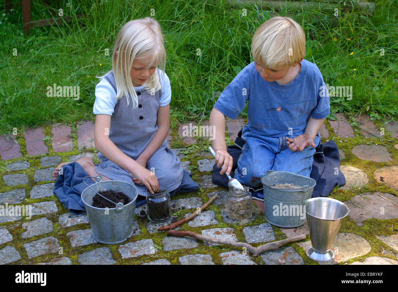 two children mixing soils to paint with earth colour, Germany Stock Photo