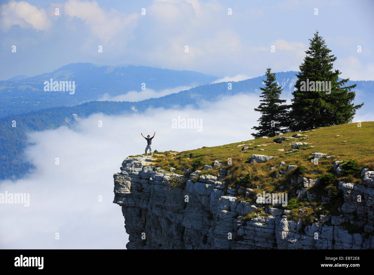 man standing at the edge of a steep face of natural rocky cirque Creux du Van, Switzerland, Schweizer Jura, Neuenburg Stock Photo