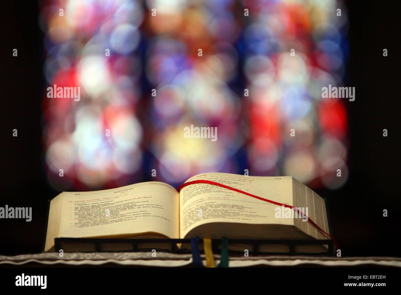 open Roman Missal and church window in background, Germany, North Rhine-Westphalia, Abteikirche Sankt Michael, Siegburg Stock Photo