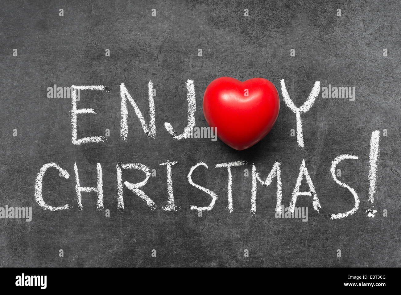 enjoy Christmas exclamation handwritten on chalkboard with heart symbol instead of O Stock Photo