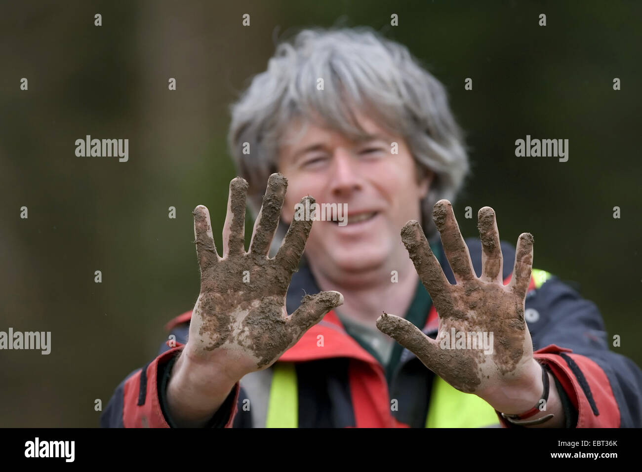 Man showing muddy hands during tree-planting session, United Kingdom, Scotland Stock Photo