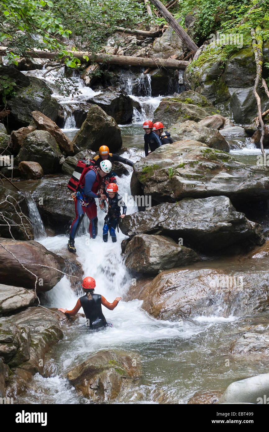 family with children walking in a brook wearing wetsuits, Austria, Kaernten Stock Photo