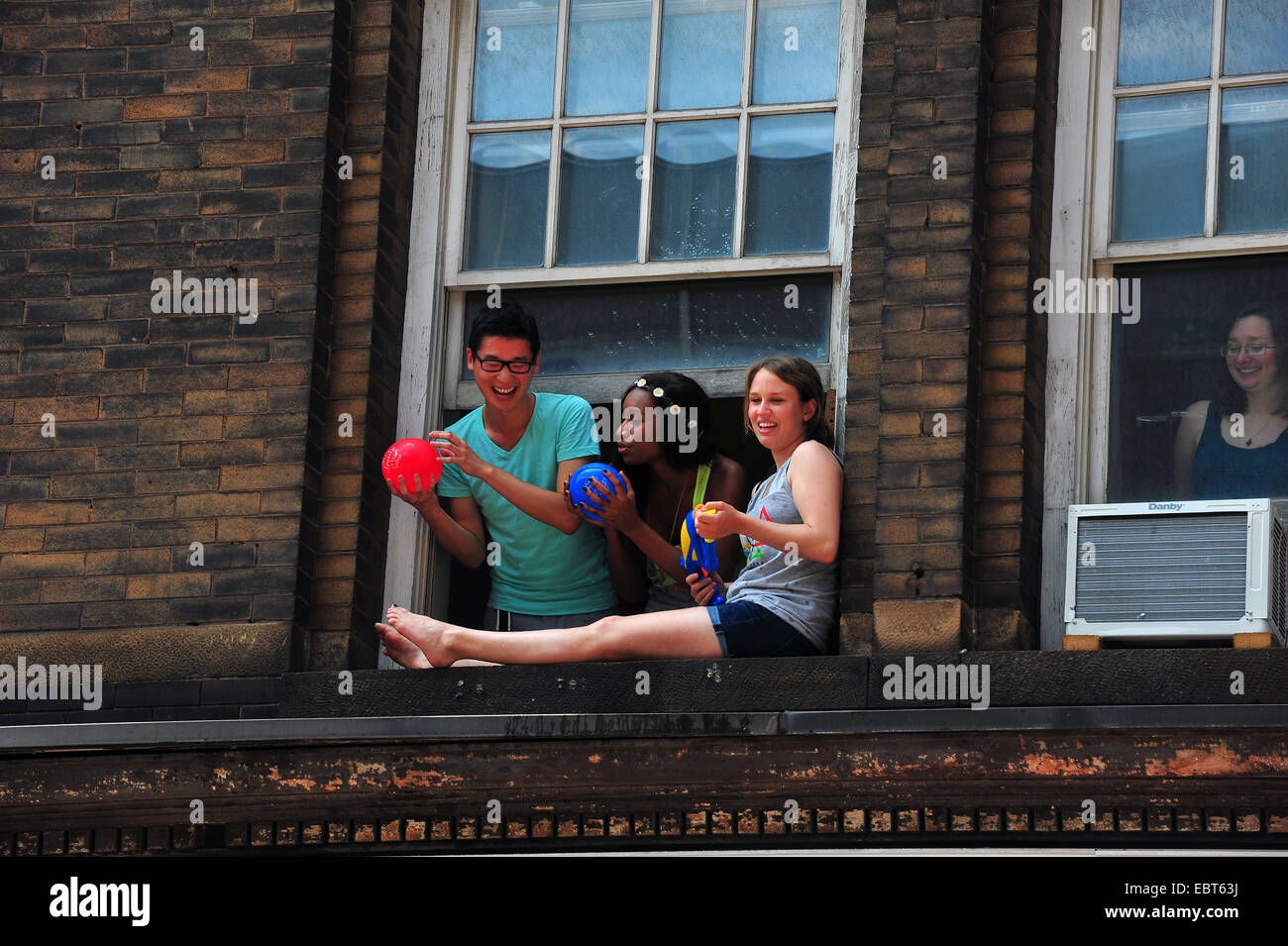 People leaning out of a window to throw water balloons at the 2014