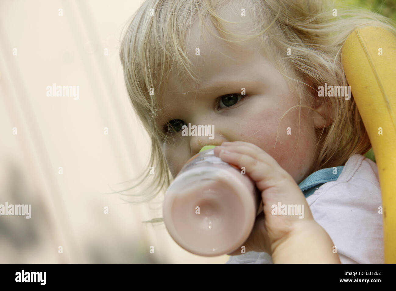 little girl with dirty face sucking at a baby bottle, Germany Stock Photo