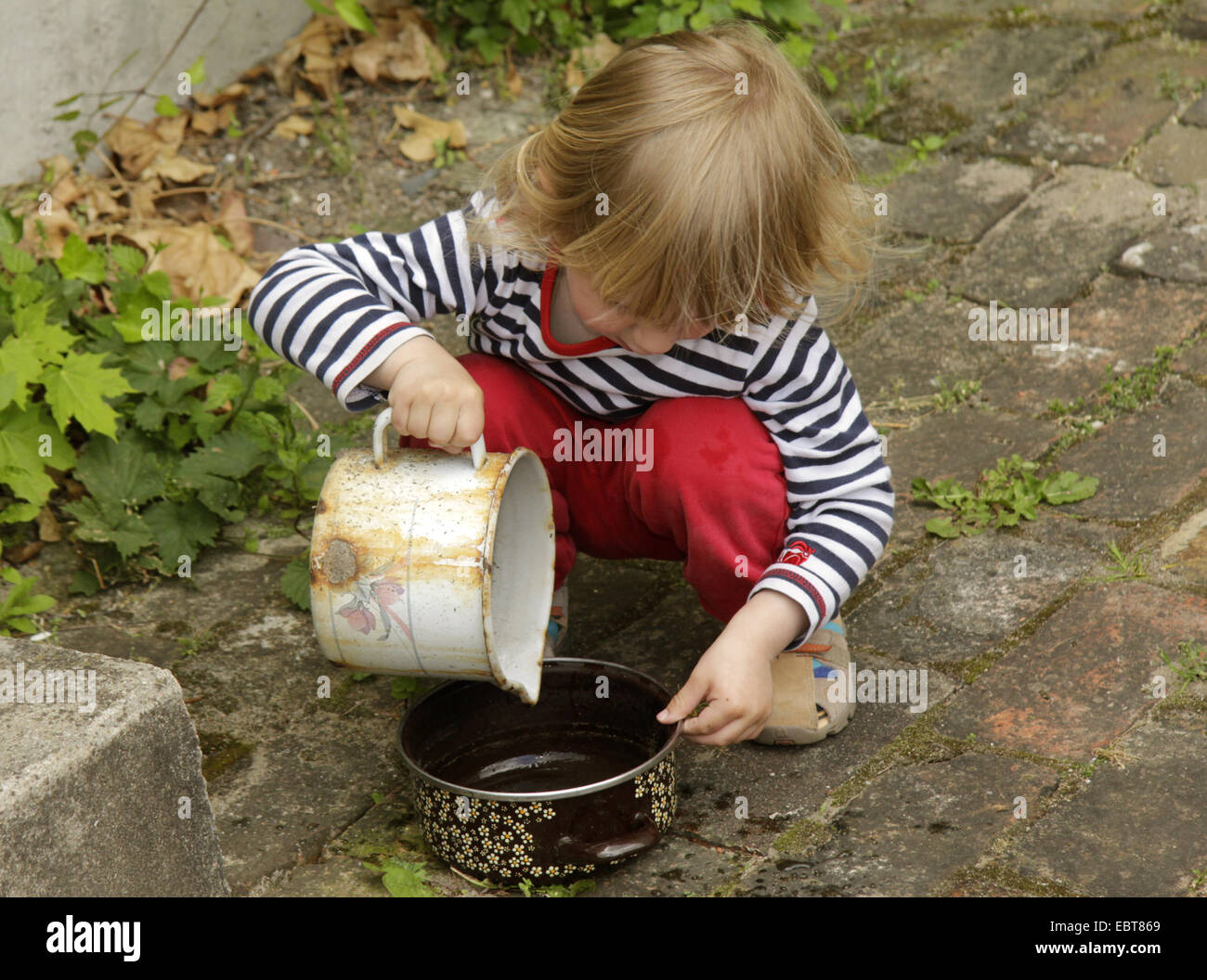 little boy playing outside with old cookware Stock Photo