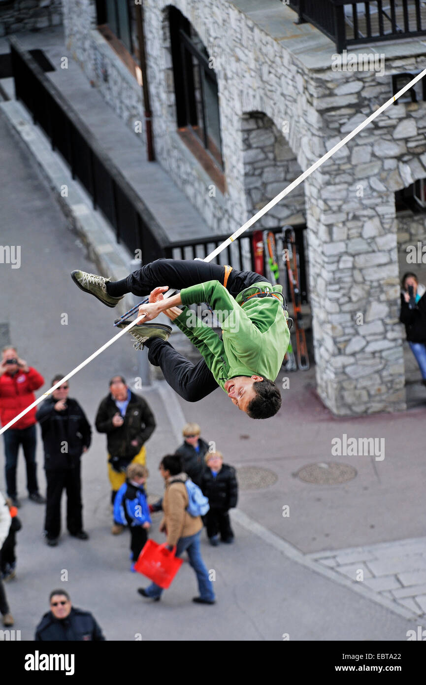man on a highline slackline over an alley loosing balance, France, Savoie, Val-dÆIsÞre Stock Photo