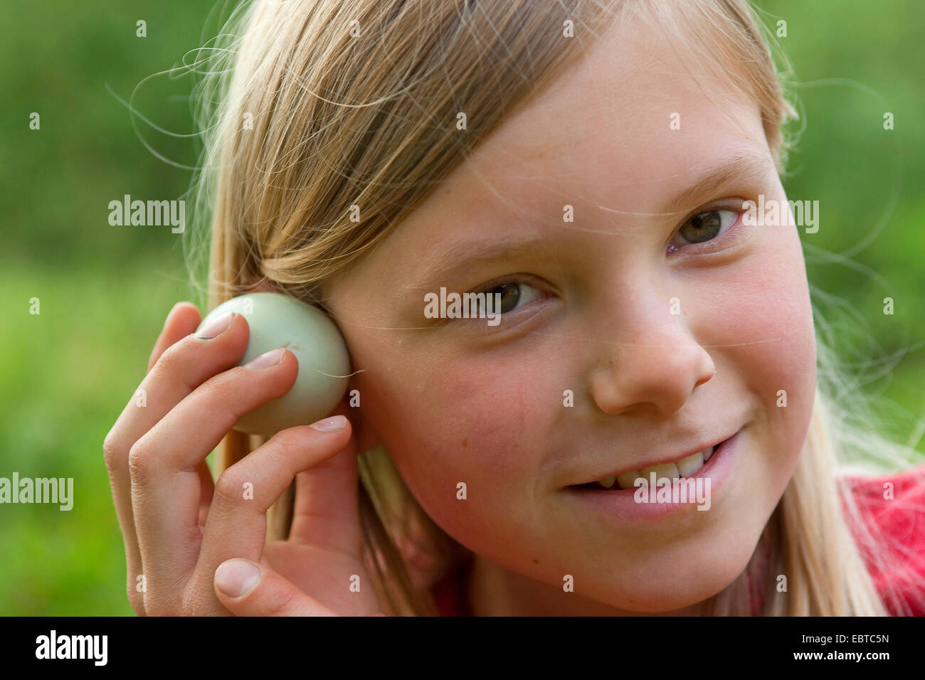 girl listening to an egg, Germany Stock Photo