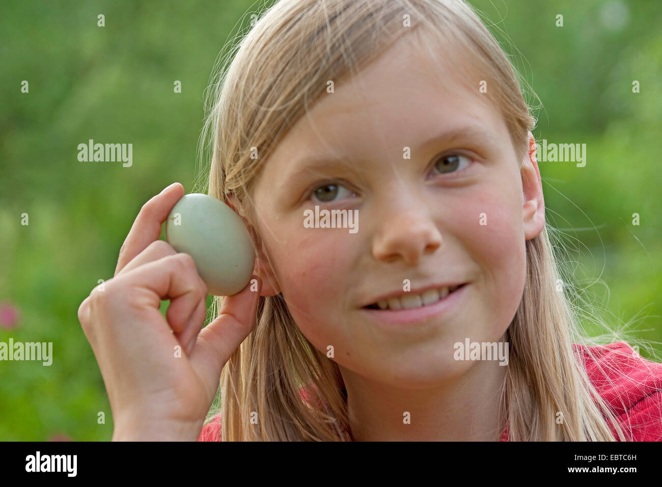 girl listening to an egg, Germany Stock Photo