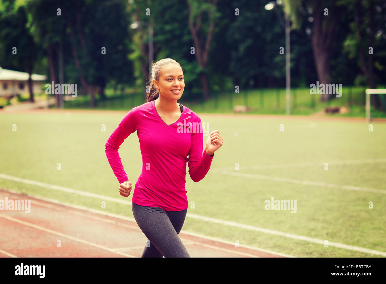 smiling woman running on track outdoors Stock Photo