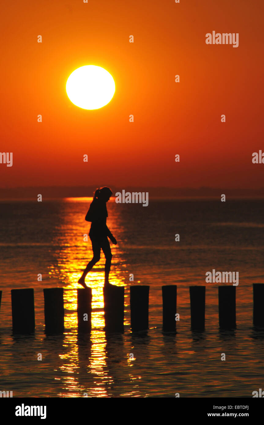woman walking on groyne at sunset, Germany, Mecklenburg-Western Pomerania Stock Photo