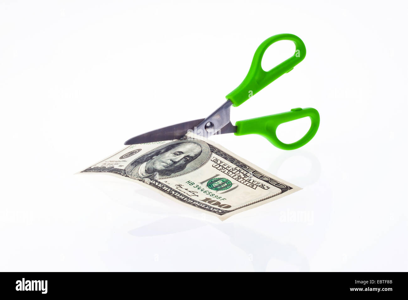 100 dollar bill being cut with scissors Stock Photo