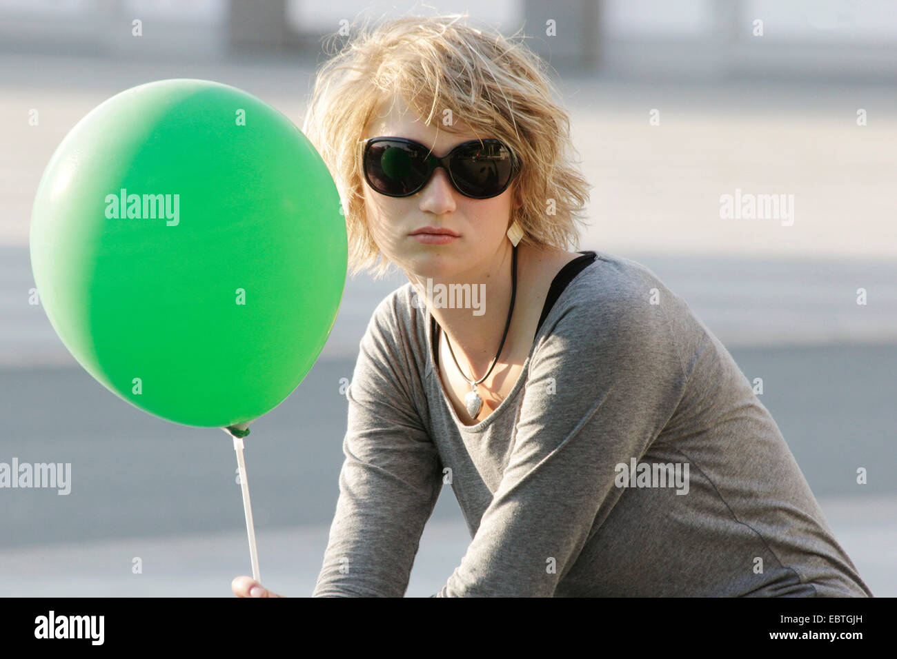 young blond woman with sunglasses and green balloon, Germany Stock Photo