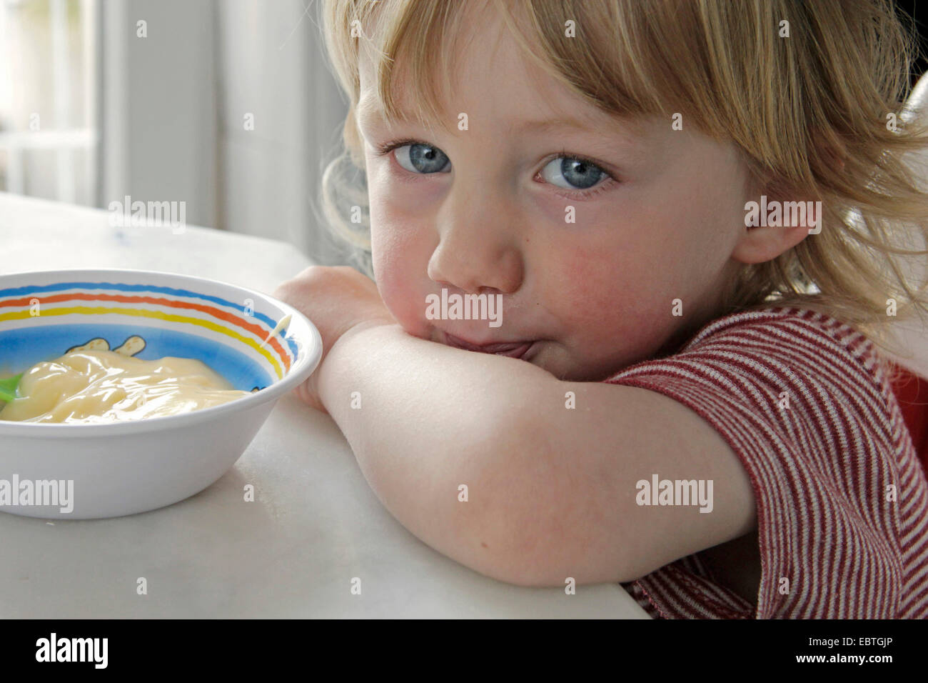 little boy sitting at the table and eating custard, Germany Stock Photo