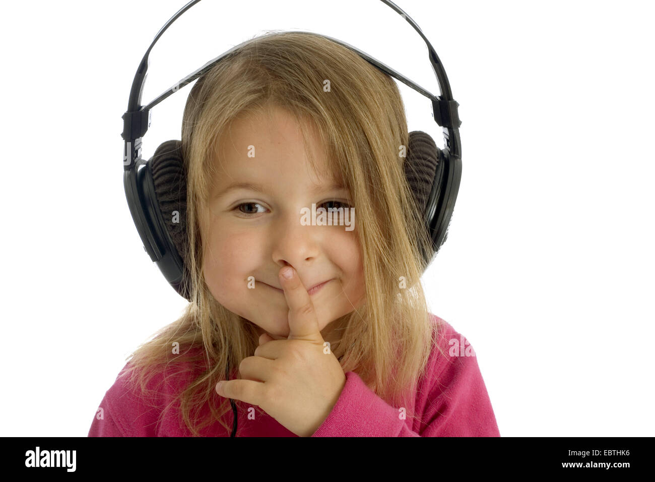 little girl smiling while listening to something by earphones Stock Photo