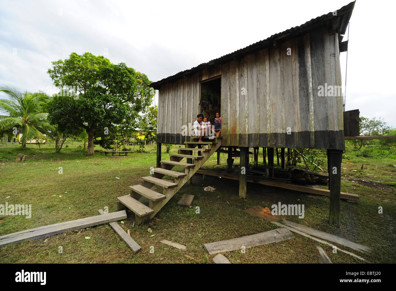 people sitting of a stairs infront of a little house of wood , Honduras, La Mosquitia, Las Marias Stock Photo