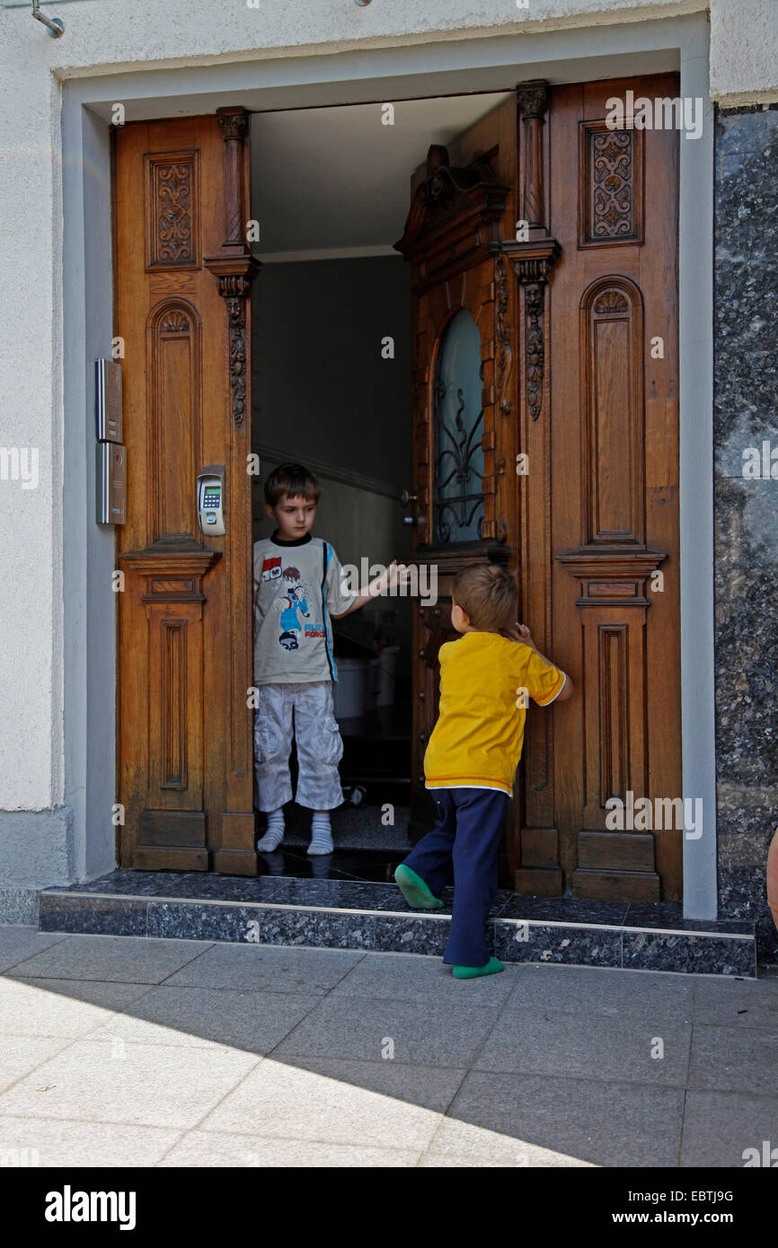 little boy opening the front door for another Stock Photo