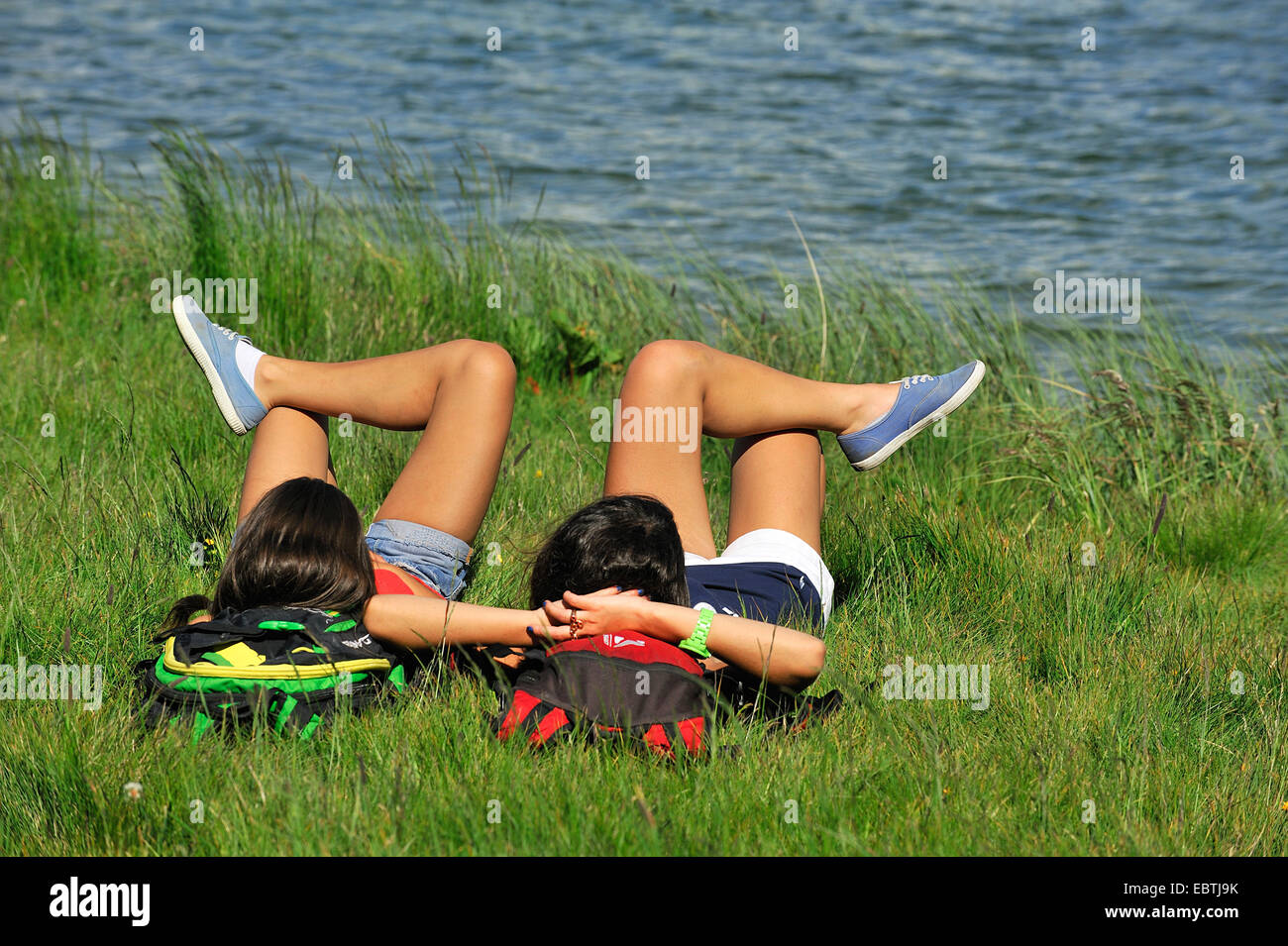 two young woman lying on mountain meadow at lake Carolay, France, Vanoise National Park Stock Photo