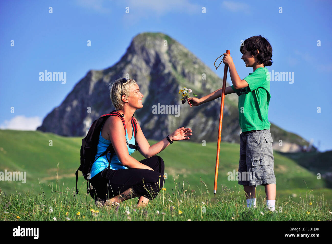boy handing over a self picked bunch of flowers to his mother during walking-tour in the Alps, France Stock Photo