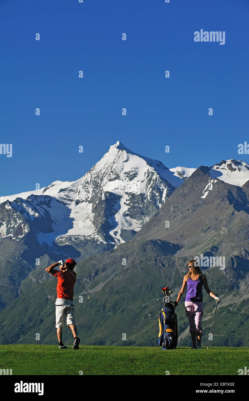 young couple playing golf, mont Pourri in background, France, Vanoise, Savoie Stock Photo