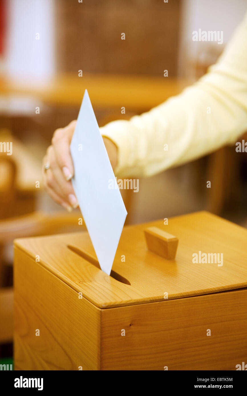 woman gives her vote at an election, a ballot box in polling station Stock Photo