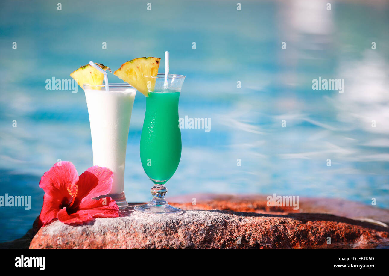 two tropical cocktails and hibiscus flower near swimming pool Stock Photo