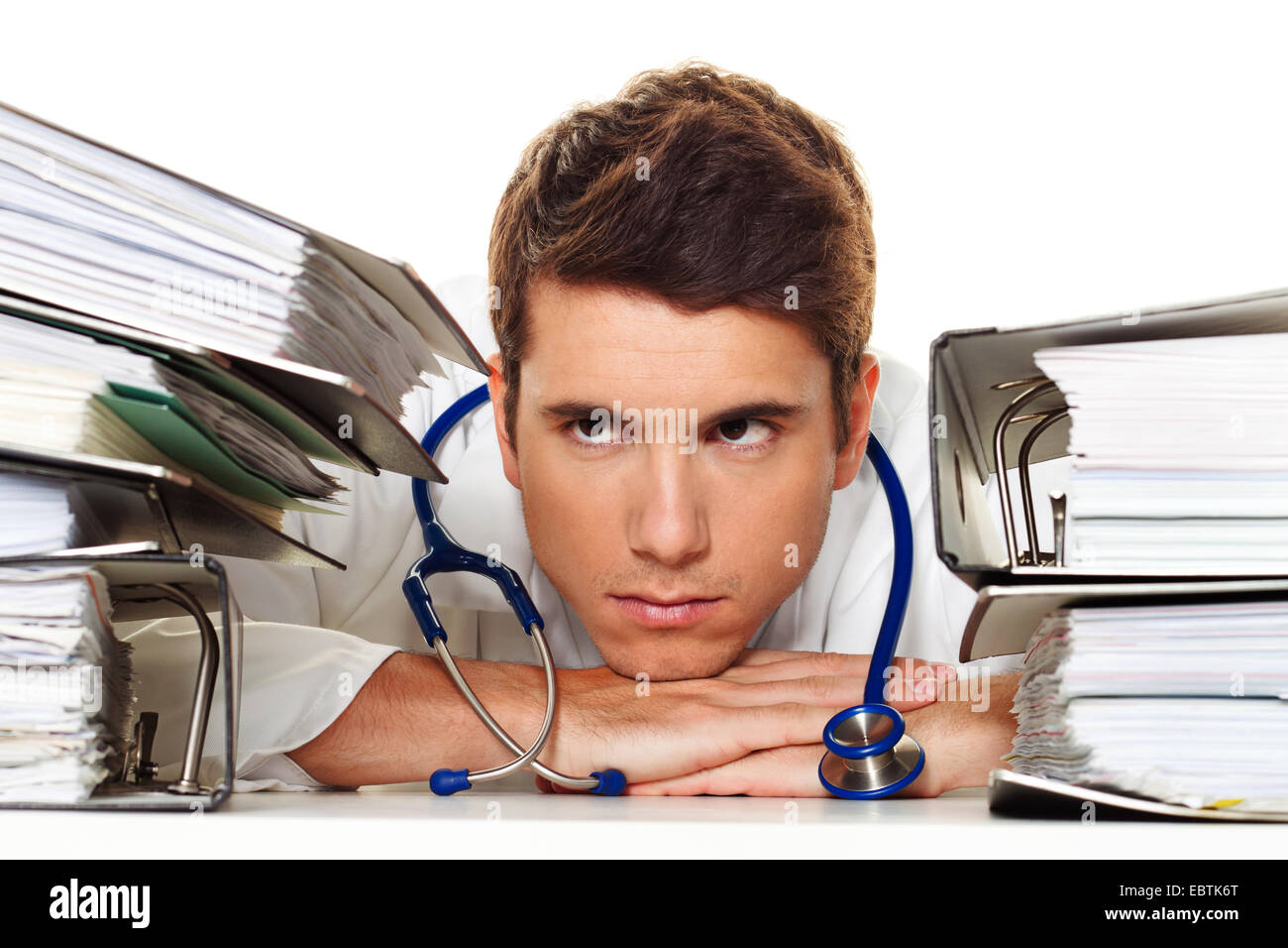 symbol picture 'bureaucracy in the public health sector': young doctor between stacks of files Stock Photo