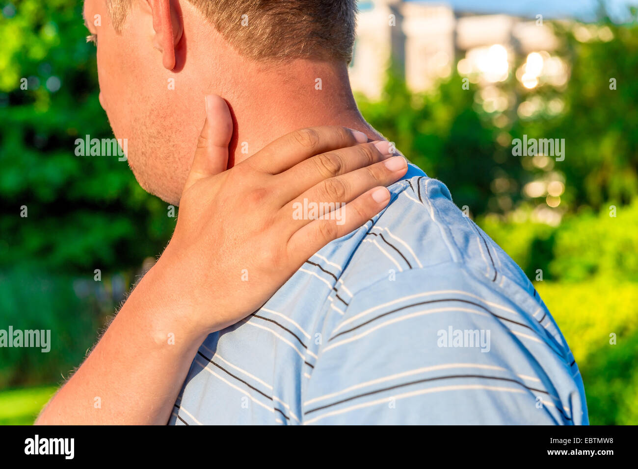 male massaging sore shoulder outdoors Stock Photo