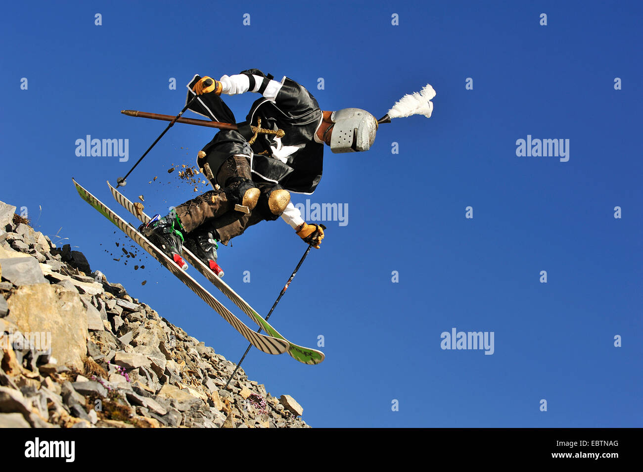 freeride skier disguised as knight going downhill on gravel slope Stock