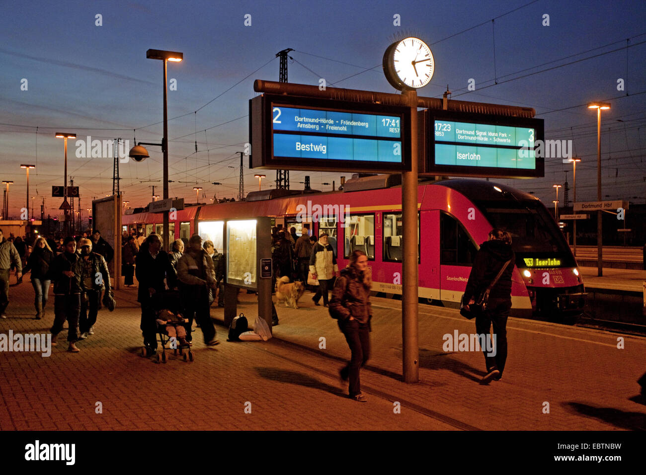 pedestrians in front of commuter train at central station in evening light, Germany, North Rhine-Westphalia, Ruhr Area, Dortmund Stock Photo