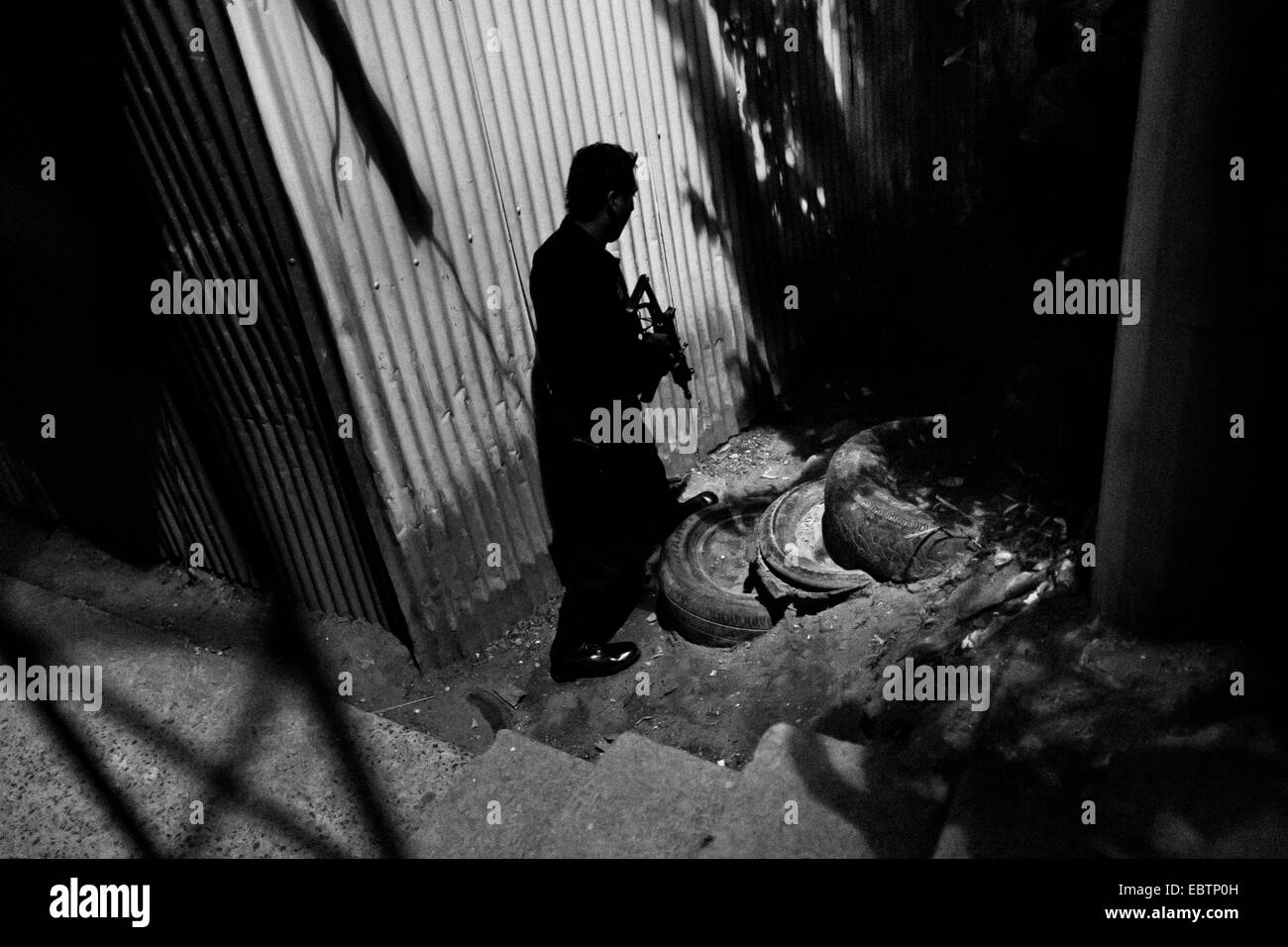 A policeman from the special emergency unit (Halcones) chases supposed gang members during the night in a gang neighbourhood of San Salvador, El Salvador, 15 December 2013. Stock Photo