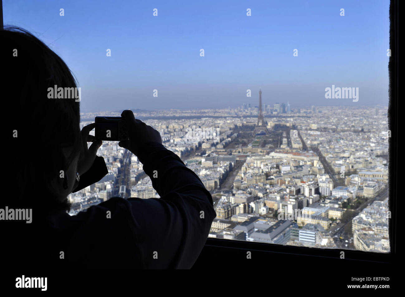 tourist taking a photo of the view from the Tour Montparnasse over the sea of houses of the city with the Eiffel Tower in the centre, France, Paris Stock Photo