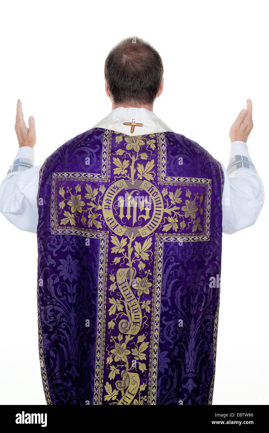 catholic priest ceremonially praying with the hands held up Stock Photo