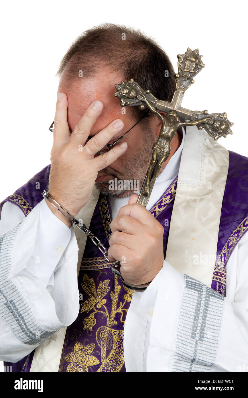 symbol picture 'child abuse in the church': priest in handcuffls holding a hand in front of his head Stock Photo